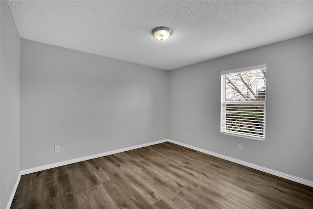 empty room with dark hardwood / wood-style flooring and a textured ceiling