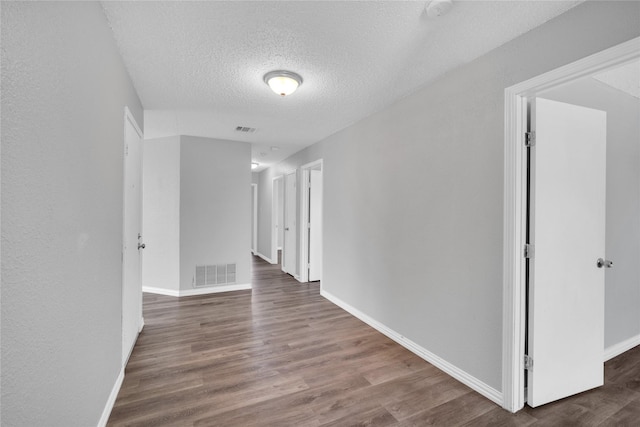 corridor featuring a textured ceiling and dark wood-type flooring