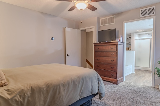 bedroom with light carpet, a textured ceiling, ceiling fan, and connected bathroom