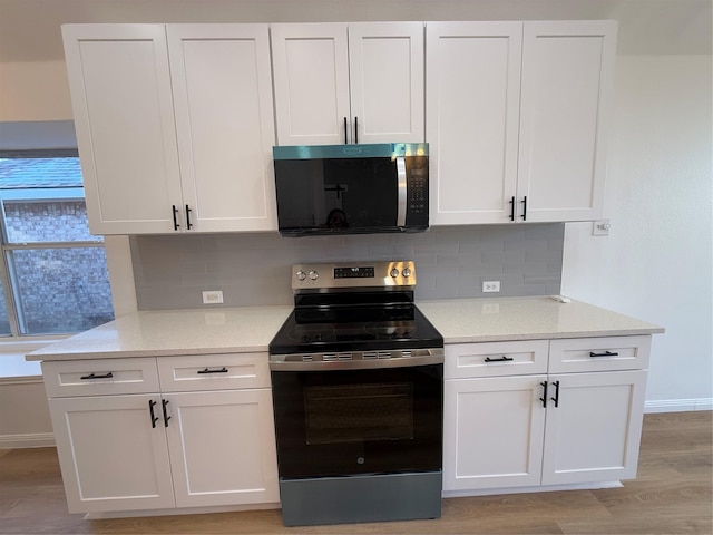 kitchen with decorative backsplash, white cabinets, light wood-type flooring, and appliances with stainless steel finishes