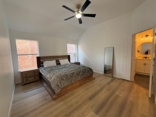 bedroom with ceiling fan, lofted ceiling, connected bathroom, and light hardwood / wood-style flooring