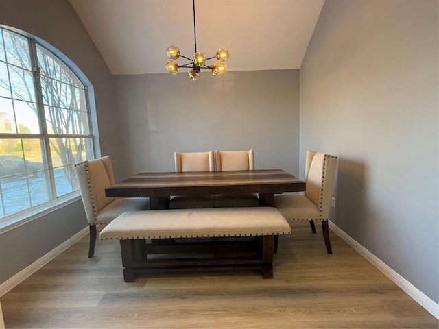 dining area featuring a healthy amount of sunlight, hardwood / wood-style flooring, an inviting chandelier, and lofted ceiling