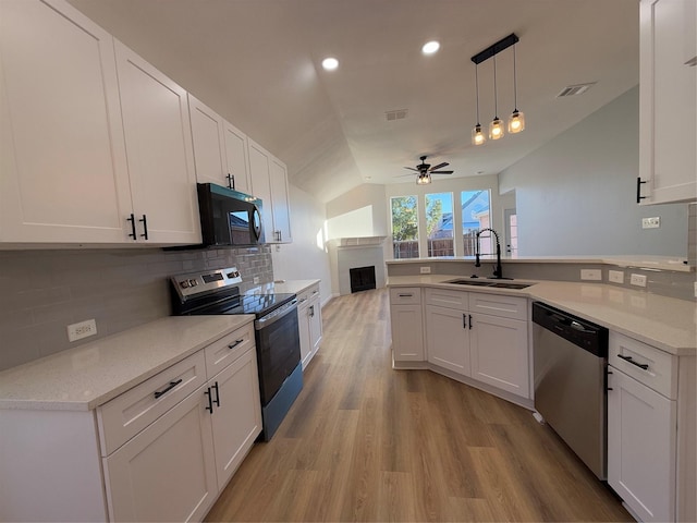 kitchen with sink, vaulted ceiling, ceiling fan, white cabinetry, and stainless steel appliances