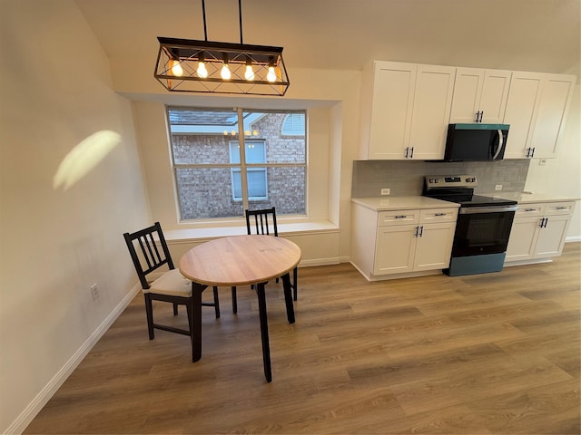 kitchen with decorative backsplash, light wood-type flooring, decorative light fixtures, white cabinets, and stainless steel electric range