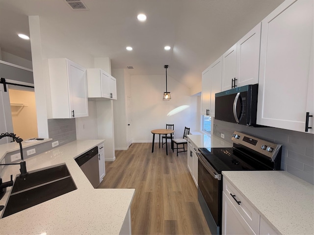 kitchen with pendant lighting, decorative backsplash, light stone counters, white cabinetry, and stainless steel appliances