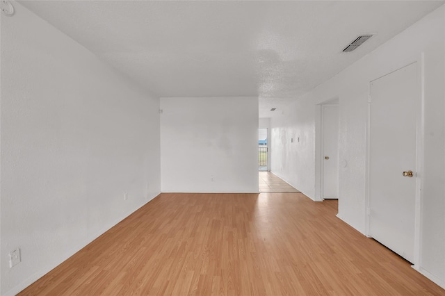 empty room with light hardwood / wood-style floors and a textured ceiling