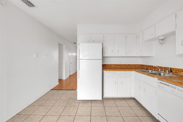 kitchen with white cabinetry, sink, light tile patterned floors, and white appliances