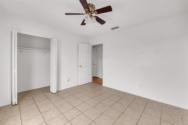 unfurnished bedroom featuring ceiling fan, light tile patterned floors, and a closet