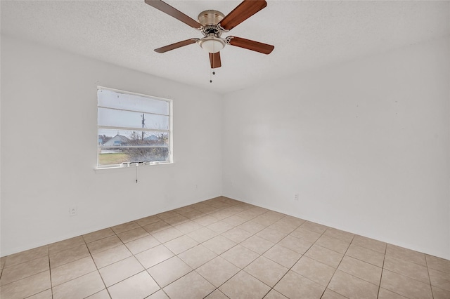 tiled empty room with ceiling fan and a textured ceiling