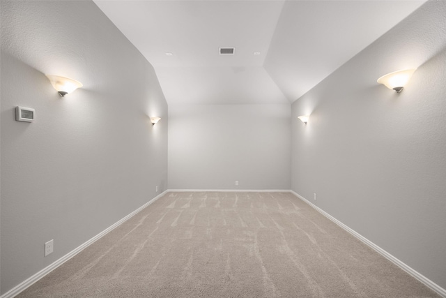 carpeted empty room featuring vaulted ceiling