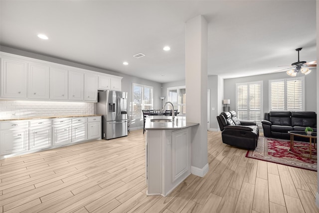 kitchen with sink, ceiling fan, stainless steel fridge, tasteful backsplash, and white cabinetry