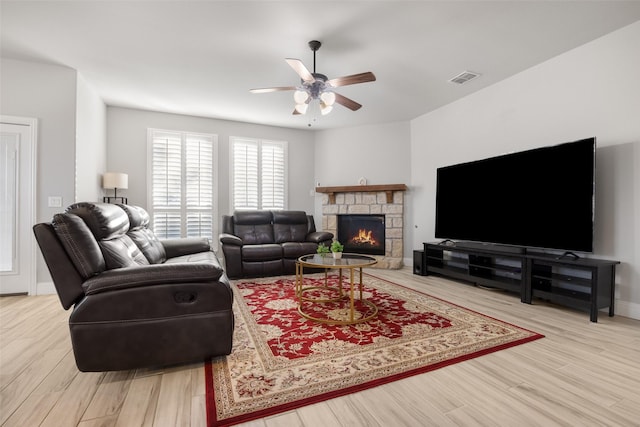 living room featuring a fireplace, light hardwood / wood-style flooring, and ceiling fan