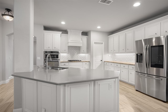 kitchen with white cabinetry, sink, light wood-type flooring, appliances with stainless steel finishes, and custom exhaust hood