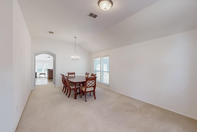 carpeted dining space featuring ceiling fan with notable chandelier and lofted ceiling