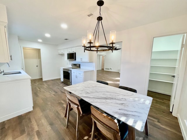 kitchen with stainless steel appliances, hanging light fixtures, sink, and white cabinets