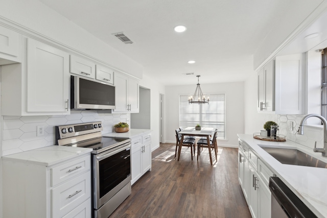 kitchen featuring pendant lighting, sink, appliances with stainless steel finishes, white cabinetry, and tasteful backsplash