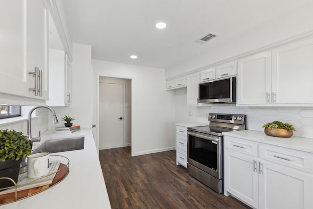 kitchen featuring sink, white cabinetry, appliances with stainless steel finishes, dark hardwood / wood-style flooring, and decorative backsplash