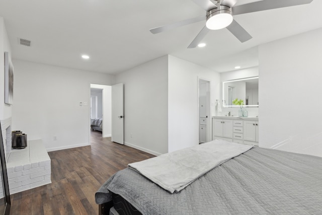 bedroom with dark hardwood / wood-style floors, connected bathroom, sink, ceiling fan, and a brick fireplace