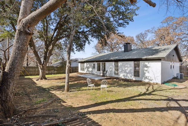 rear view of property with central AC and a lawn