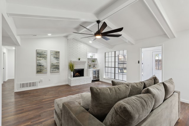 living room featuring lofted ceiling with beams, ceiling fan, a brick fireplace, and dark hardwood / wood-style flooring