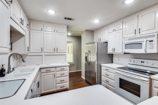 kitchen featuring sink, a textured ceiling, dark hardwood / wood-style floors, white appliances, and white cabinets