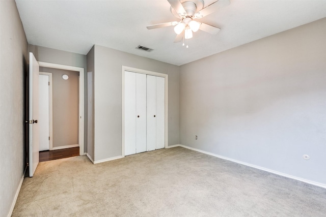 unfurnished bedroom featuring light carpet, ceiling fan, and a closet