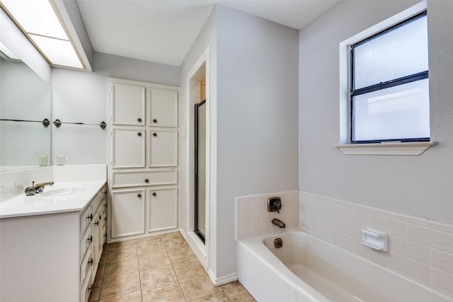 bathroom with tile patterned flooring, vanity, a skylight, and independent shower and bath