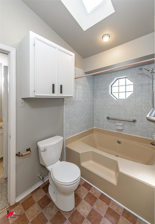 bathroom with toilet, tiled shower / bath, and vaulted ceiling with skylight