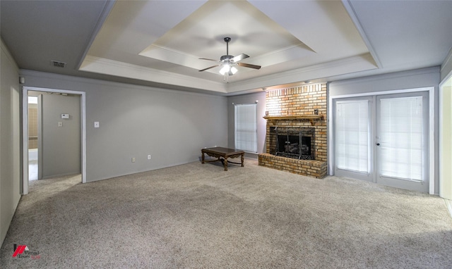 unfurnished living room featuring crown molding, carpet flooring, a tray ceiling, and a fireplace