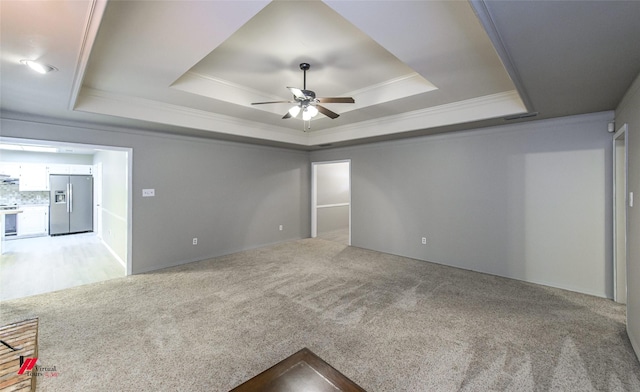 unfurnished room with a raised ceiling, crown molding, light colored carpet, and ceiling fan