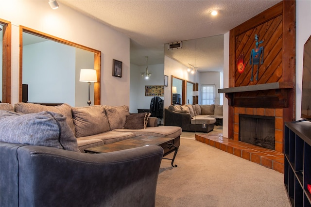 carpeted living room featuring a notable chandelier, a textured ceiling, and a tile fireplace