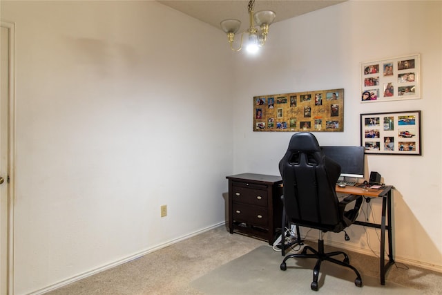 carpeted home office featuring a chandelier