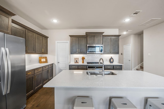 kitchen with sink, backsplash, a kitchen breakfast bar, light stone counters, and stainless steel appliances