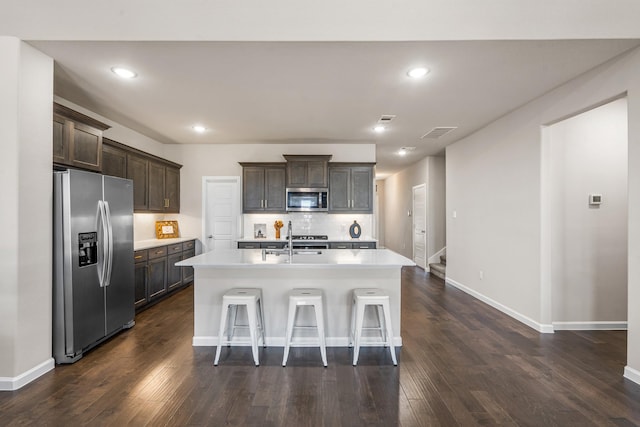 kitchen featuring sink, a breakfast bar area, a kitchen island with sink, dark brown cabinetry, and stainless steel appliances