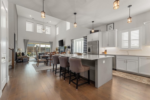 kitchen with pendant lighting, backsplash, white cabinets, a kitchen island, and stainless steel appliances