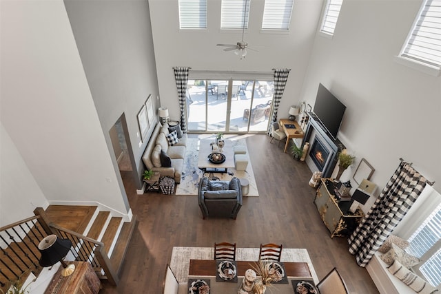 living room featuring dark hardwood / wood-style flooring, a towering ceiling, and ceiling fan