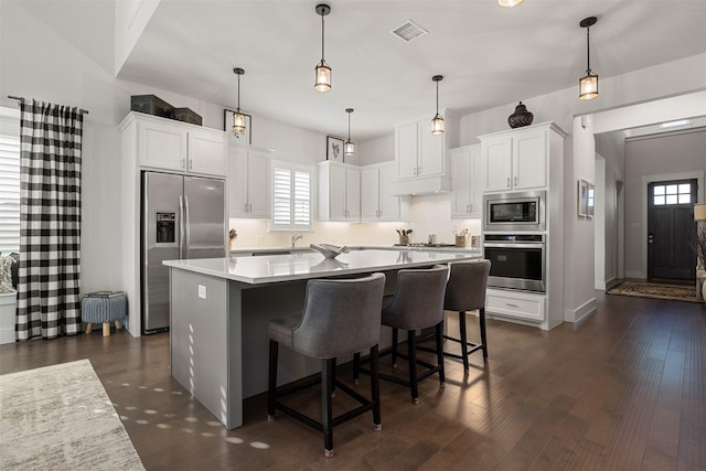 kitchen featuring pendant lighting, stainless steel appliances, white cabinetry, and a kitchen island