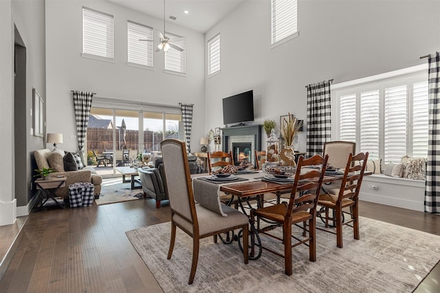 dining area with ceiling fan, dark hardwood / wood-style flooring, and a high ceiling