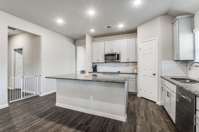 kitchen featuring sink, dark hardwood / wood-style floors, a kitchen island, stone counters, and stainless steel appliances