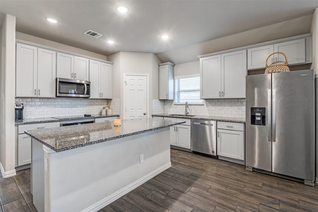 kitchen with stainless steel appliances, a center island, sink, and white cabinets