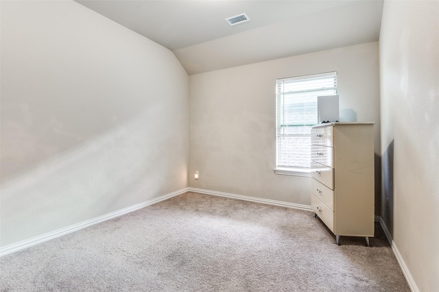 unfurnished room featuring vaulted ceiling and light carpet