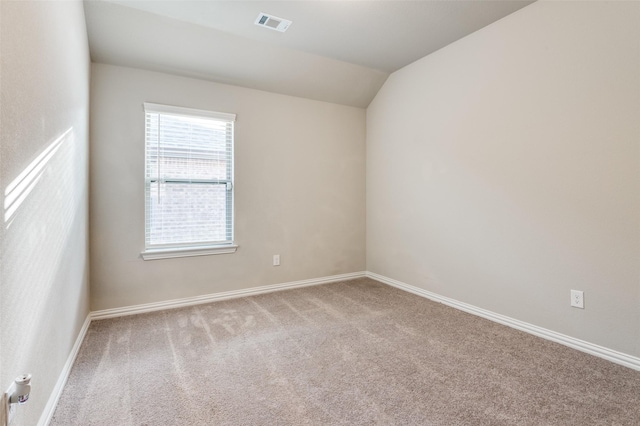 spare room featuring carpet and lofted ceiling