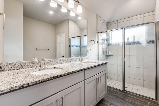 bathroom with vanity, hardwood / wood-style floors, a shower with shower door, and lofted ceiling