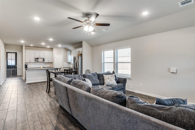 living room featuring dark wood-type flooring and ceiling fan