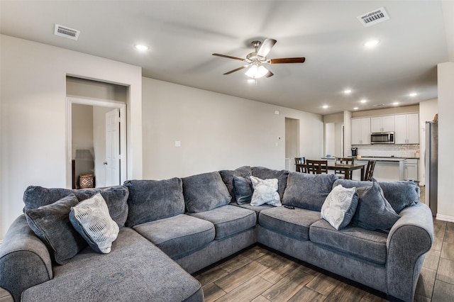 living room featuring ceiling fan and dark hardwood / wood-style flooring