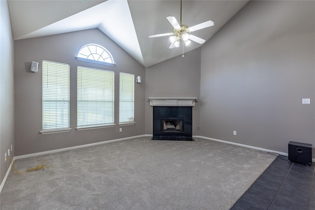 unfurnished living room with ceiling fan, dark carpet, lofted ceiling, and a tiled fireplace