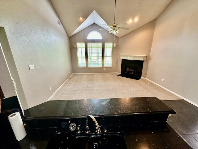 living area featuring a ceiling fan, a fireplace with flush hearth, lofted ceiling, carpet flooring, and baseboards