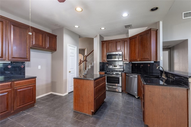 kitchen with sink, a center island, stainless steel appliances, backsplash, and dark stone countertops