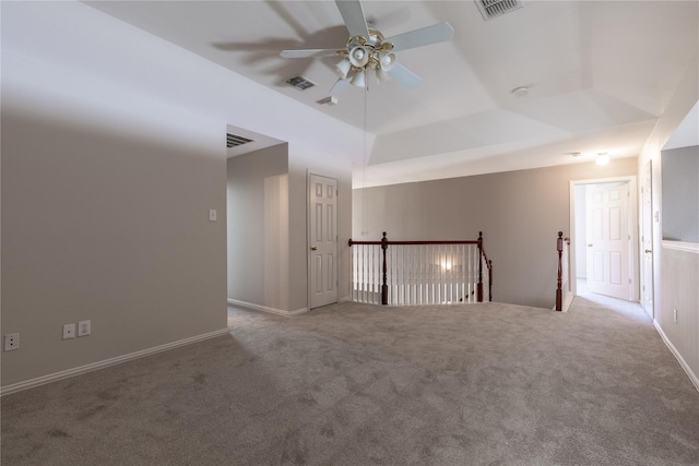 empty room with carpet floors, a tray ceiling, ceiling fan, and lofted ceiling