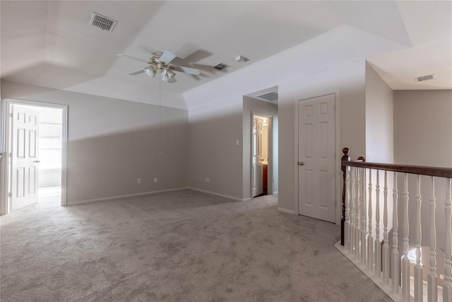 spare room featuring ceiling fan, light colored carpet, and vaulted ceiling